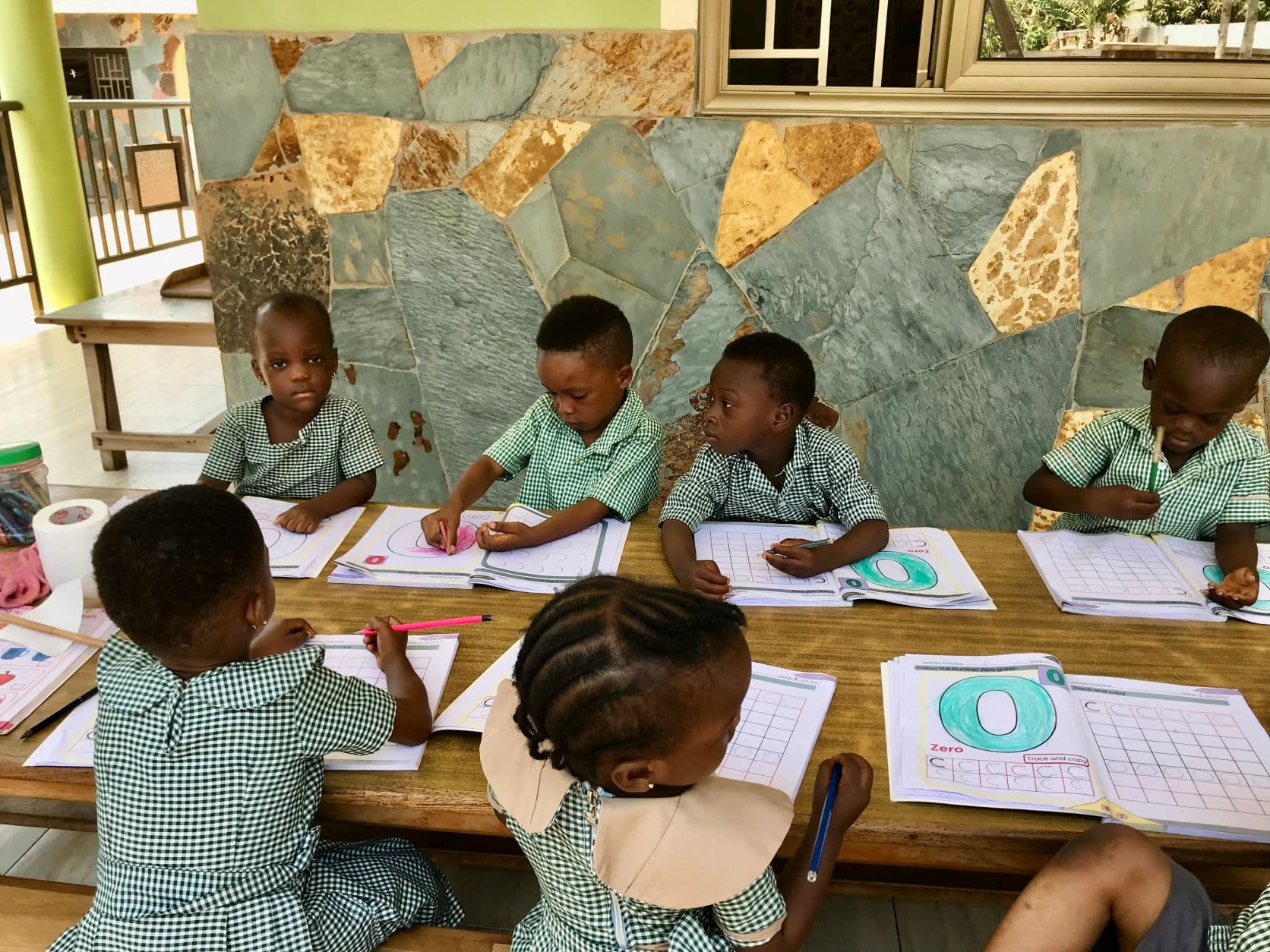 Kinderen in groene schooluniformen werken samen aan hun lessen in de klas